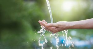 Water,Pouring,In,Woman,Hand,On,Nature,Background,,Environment,Issues